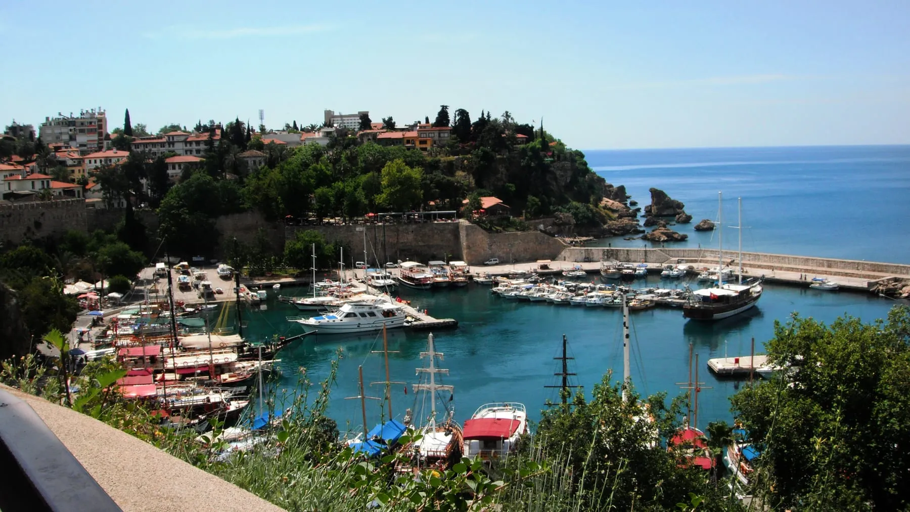 Antalya'daki eski limanda tekneler ve arkada sahil